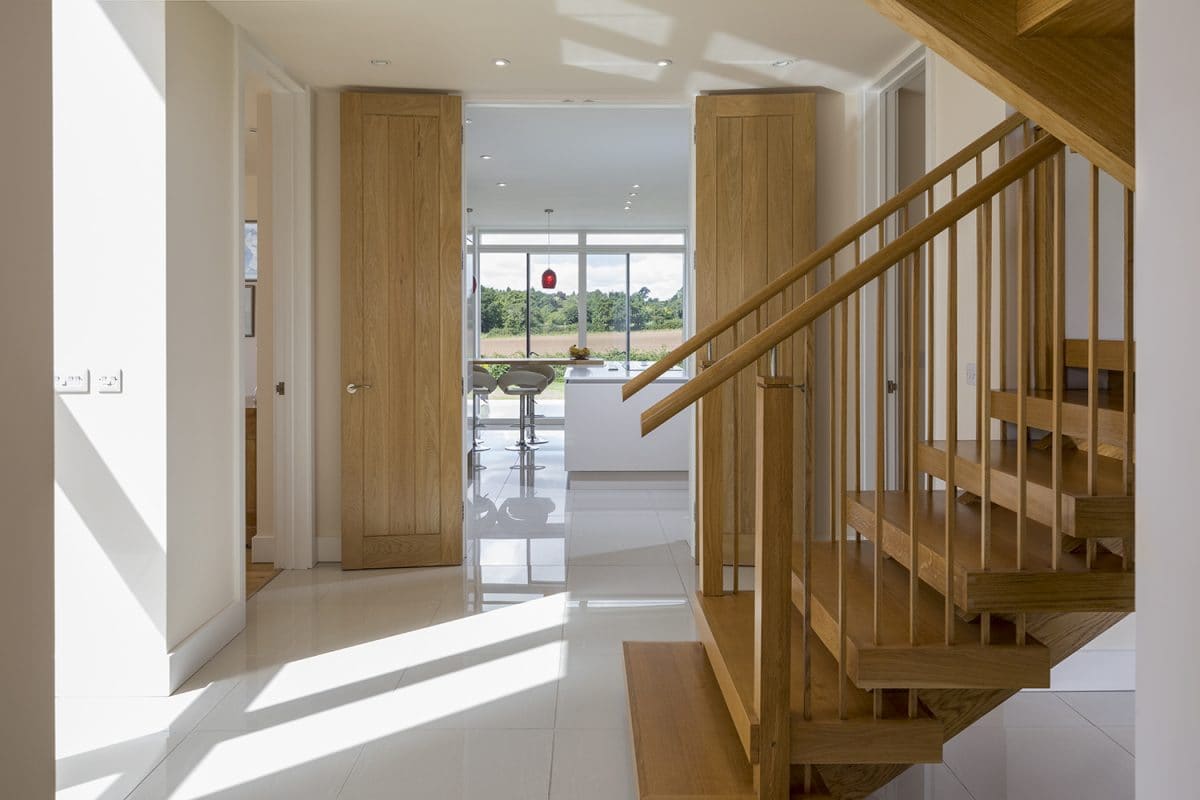 Bespoke wooden staircase rising from tiled hallway, new build in Worcestershire