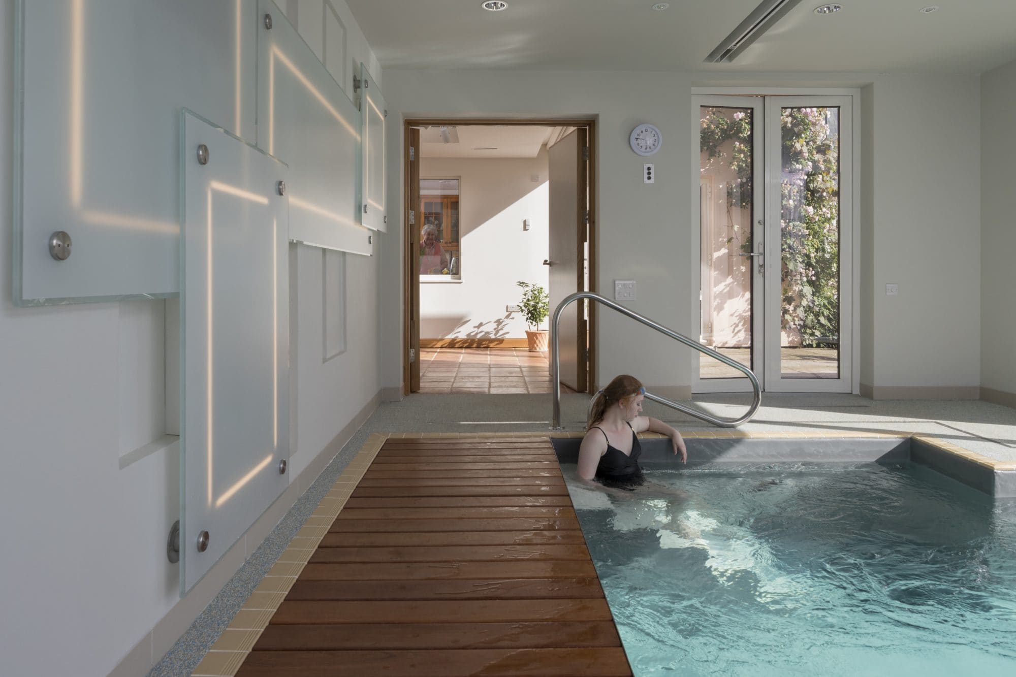 Wooden walkway alongside indoor swimming pool.