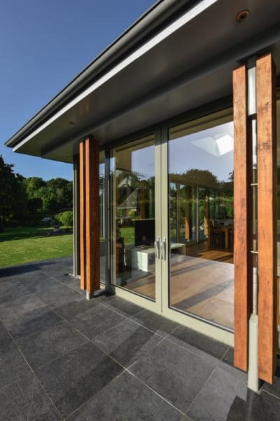 Exterior of home extension, close up of glazed sliding doors closed with timber columns either side. Communion Architects Herefordshire