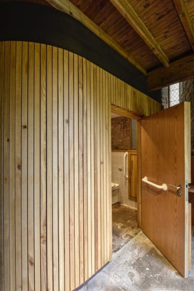 A timber cube-like structure, door open to reveal an accessible toilet, St Michael and All Angels, church re-ordering.