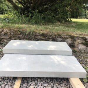 Two white stone slabs, approximately 1 foot by 2 feet, which will be laid as steps in a landscaped garden