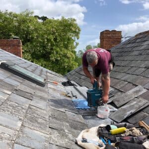 a builder working on a slate tiled roof, repairing the lead guttering on a Georgian house, listed building.