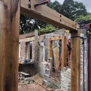 On a construction site for a grade 2 listed building in Herefordshire, creation an extension. Here the construction works are securing timber doorways made of thick oak beams between breeze block walls. Communion Architects, Herefordshire