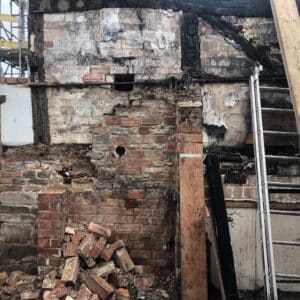 Wall from a fire damaged cottage. The timber framed walls are filled in with charred brick from the recent fire. The current structure is precarious and needs securing. Communion Architects, Herefordshire.