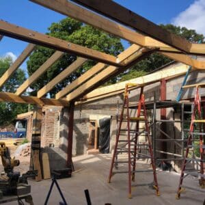 A timber frame for an extension - the blue sky and green fields can be viewed through the frame - will for a new kitchen - communion architects Hereford