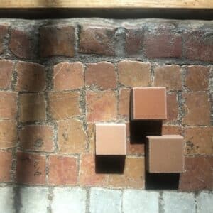 Victorian Mosaic tile floor in a church, three new tiles sit on top of the original tiled floor, all the tiles are varying ceramic shades. The new tiles will fill the gaps in the mosaic elsewhere in the church. The colours have been carefully matched to reflect the varying tones