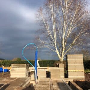 Concrete slabs laid on a new floor for a new dwelling occupy the lower third of the image, the middle third show shows piles of more concrete slabs while a grey and blue winter sky rises up in the background. Communion Architects, Herefordshire