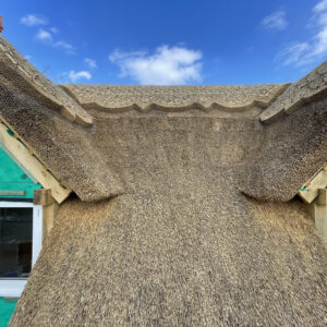 Two dormer windows with thatch and decorative ridges at the apex of the dormers and roof. Communion Architects, Hereford, Herefordshire.