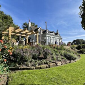 A rural cottage with a new sensitive extension nestled in a green garden under blue skies, communion architects Hereford.