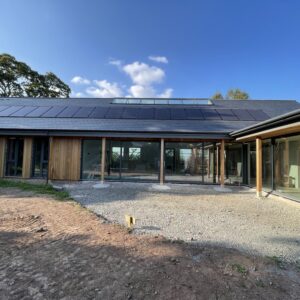 a L shaped house, single storey with a slate roof, full height glazing for the walls and timber columns supporting overhanging eaves. Communion Architects, Hereford.
