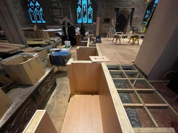 image from site in a church reordering project. Materials and boxes scattered across the floor of a medieval church ready to be transformed. Communion Architects Hereford.