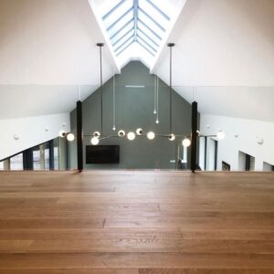 View from mezzanine in a new build house. Apex windows, glass balustrade, steel and glass light fixtures. Communion Architects Hereford
