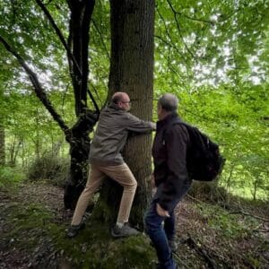 A man hugging a tree in the forest. Communion Architects Hereford