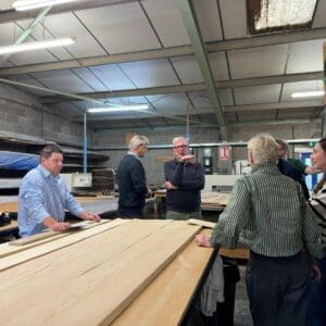 A group of people at a wood showroom, looking at samples of ash and maple veneer. Communion Architects Hereford
